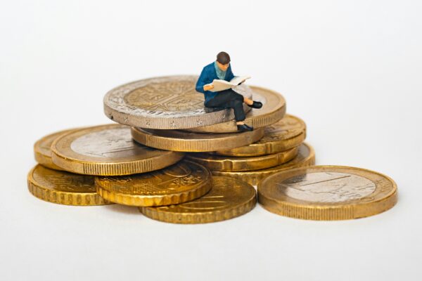 kleine Figur sitzt auf Euromünzen. Veranschaulicht das Privileg Klasse