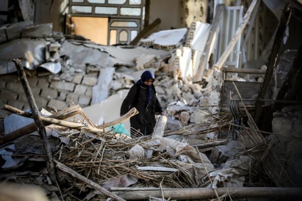 Eine Person steht in einem Erdbeben-zerstörtem Haus.